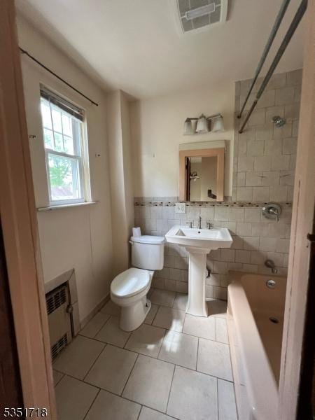 bathroom with visible vents, tile walls, tile patterned flooring, toilet, and radiator heating unit