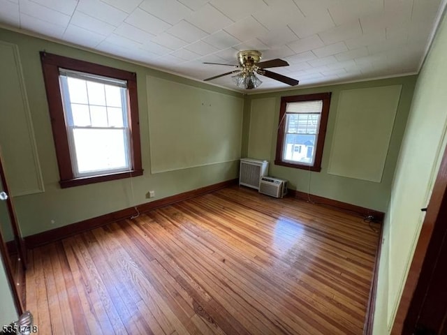 unfurnished room featuring plenty of natural light, a ceiling fan, baseboards, and hardwood / wood-style flooring