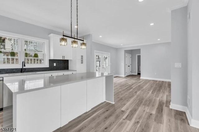 kitchen featuring french doors, a sink, a kitchen island, baseboards, and decorative backsplash