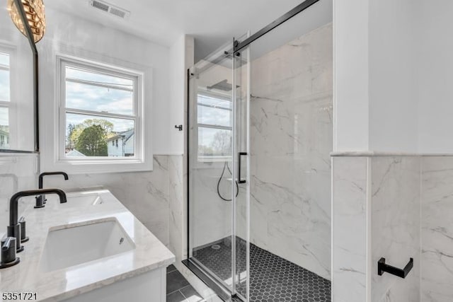 full bath with visible vents, a sink, and a marble finish shower