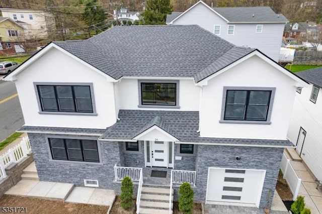 view of front of house with stone siding, stucco siding, roof with shingles, and a garage