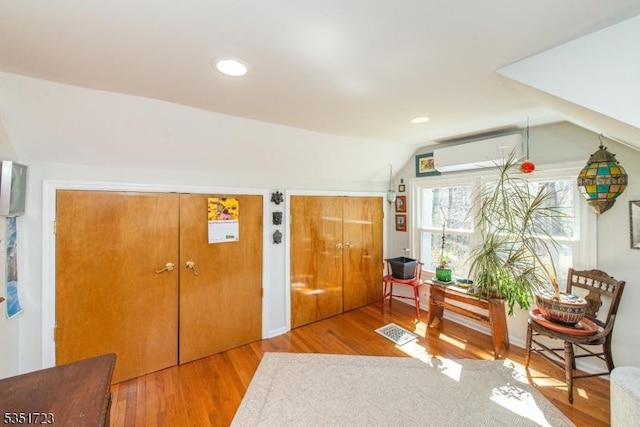 entrance foyer featuring a wall mounted air conditioner, vaulted ceiling, wood finished floors, and recessed lighting