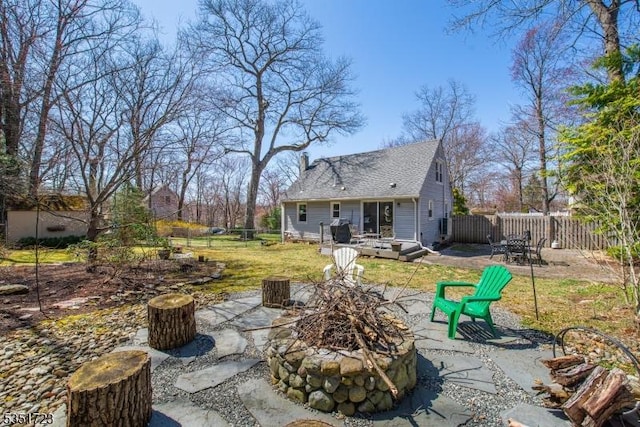 back of house featuring a fenced backyard, a wooden deck, a patio area, a lawn, and an outdoor fire pit