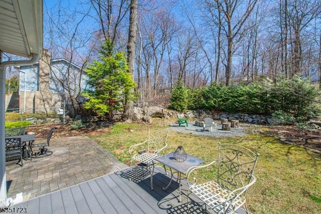 wooden terrace featuring a lawn, a patio, and fence