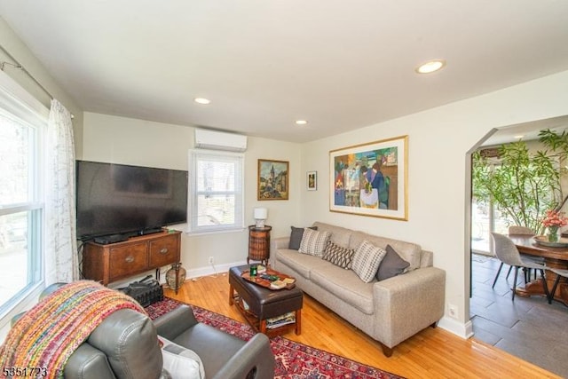 living room with a wall mounted AC, baseboards, light wood finished floors, and recessed lighting