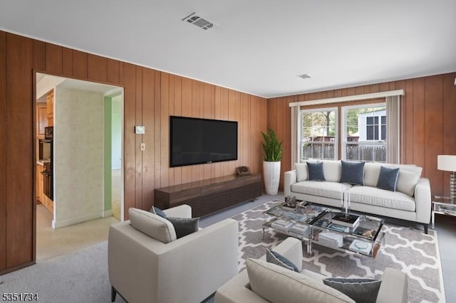 living area with visible vents, baseboards, and wooden walls