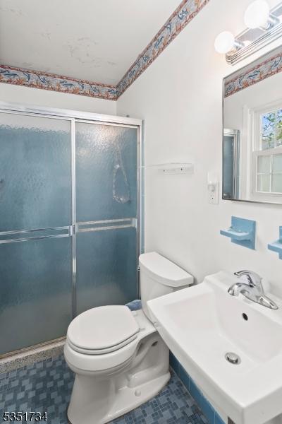 bathroom with a sink, tile patterned flooring, a stall shower, and toilet