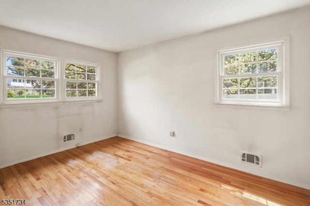 unfurnished room featuring visible vents, light wood finished floors, and baseboards