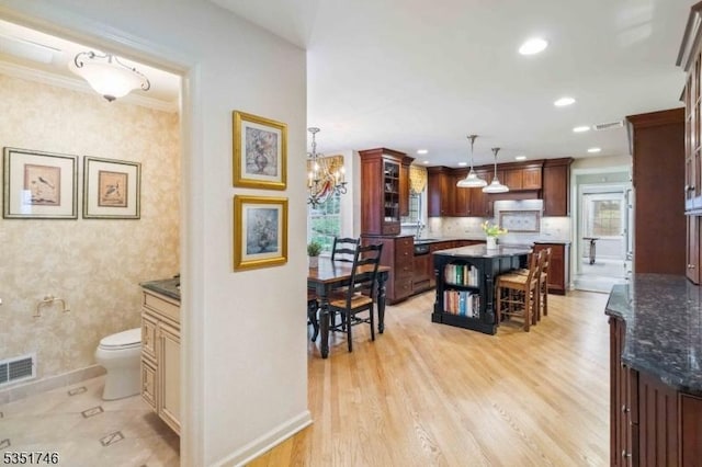 kitchen with light wood finished floors, plenty of natural light, baseboards, a kitchen island, and visible vents