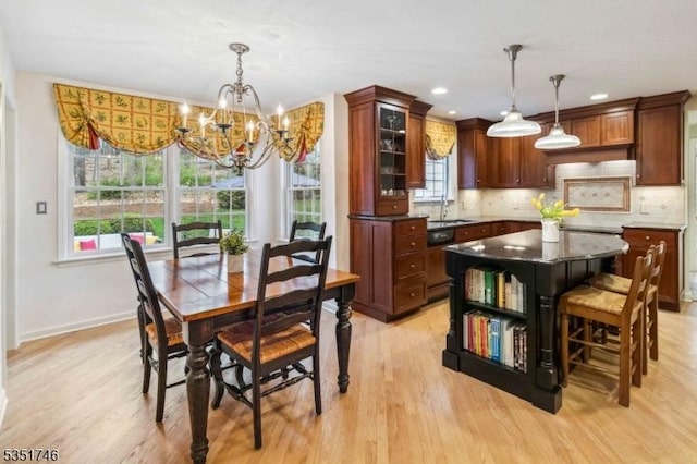 dining area with light wood-style floors, baseboards, a wealth of natural light, and a notable chandelier