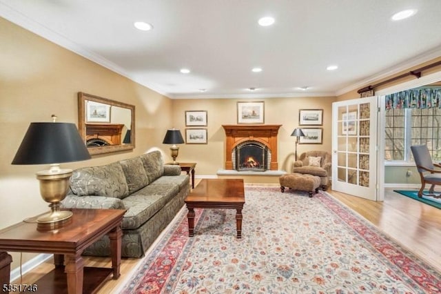 living room featuring crown molding, baseboards, a lit fireplace, and wood finished floors