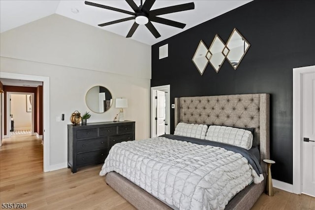 bedroom featuring visible vents, baseboards, light wood-style flooring, high vaulted ceiling, and ceiling fan
