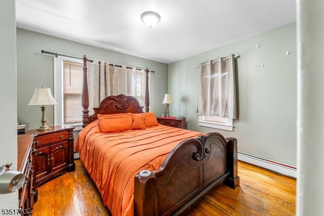 bedroom featuring wood finished floors and baseboard heating