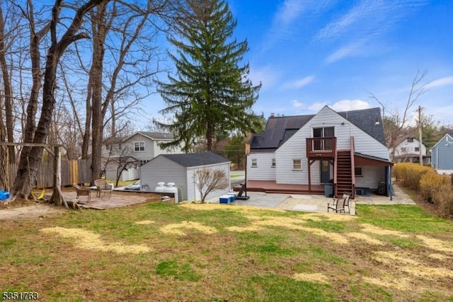 back of house featuring an outdoor structure, a wooden deck, fence, a patio, and a storage shed