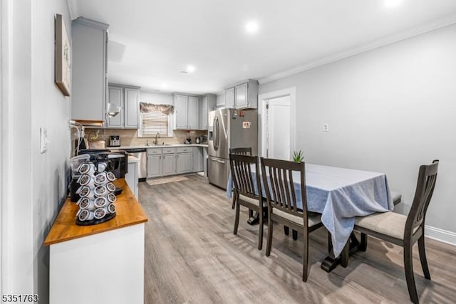 dining space with recessed lighting, ornamental molding, and light wood-style floors