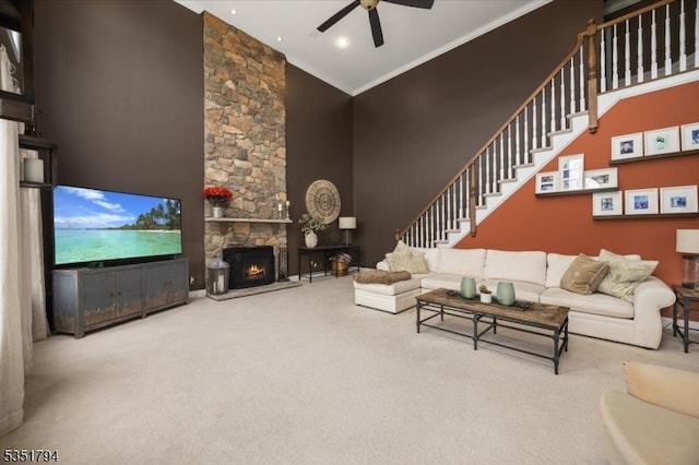 carpeted living area featuring recessed lighting, stairway, a ceiling fan, a stone fireplace, and ornamental molding
