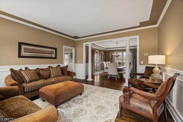 living area with crown molding, wainscoting, wood finished floors, and ornate columns