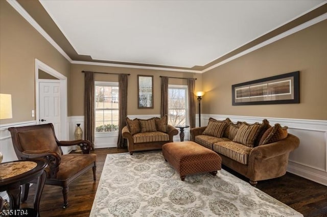 living area with dark wood-type flooring, a wainscoted wall, and ornamental molding