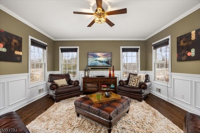 living area with a ceiling fan, visible vents, a wainscoted wall, and dark wood-style floors