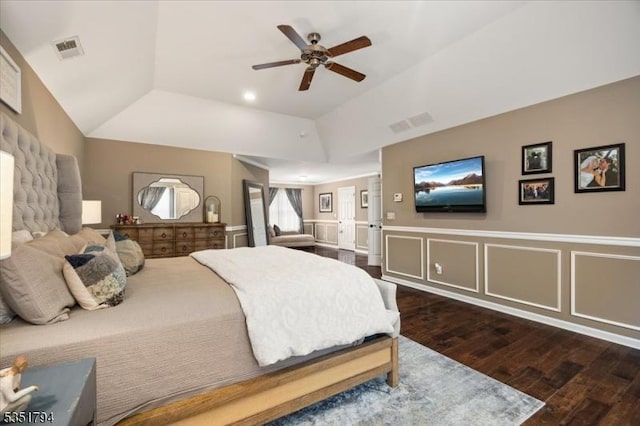 bedroom with a raised ceiling, visible vents, wainscoting, and wood finished floors