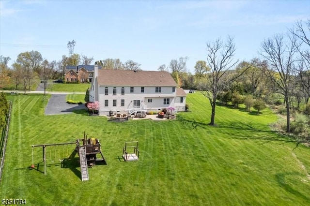 back of property featuring a chimney, an outdoor fire pit, and a lawn