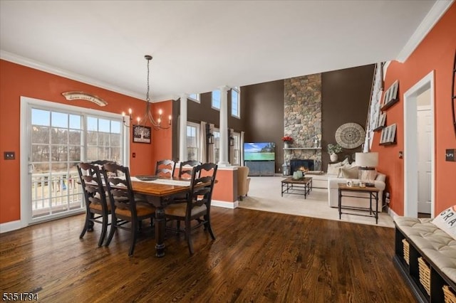 dining area featuring a fireplace, a notable chandelier, dark wood-type flooring, baseboards, and ornamental molding