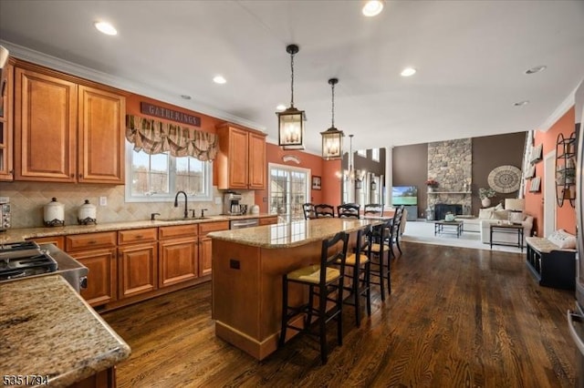 kitchen with a kitchen breakfast bar, brown cabinets, a sink, a kitchen island, and dark wood finished floors