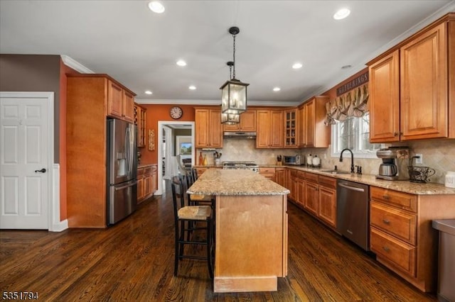 kitchen featuring appliances with stainless steel finishes, brown cabinets, a kitchen island, and a sink