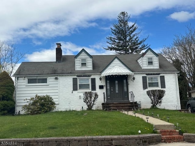 new england style home with brick siding, a chimney, and a front lawn