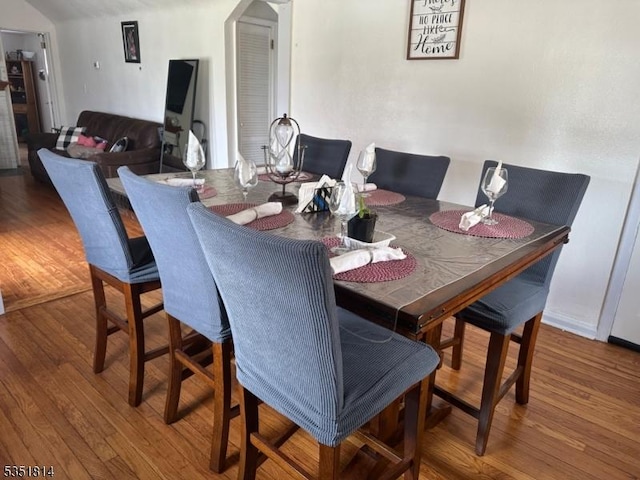 dining room with arched walkways and wood finished floors