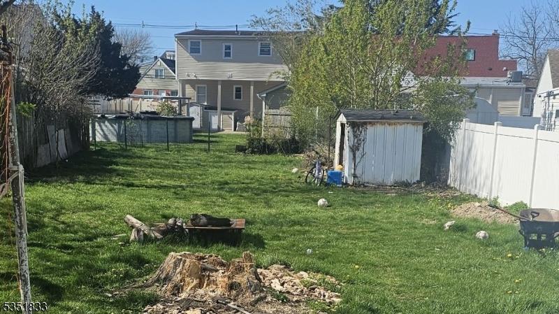 view of yard with fence, an outdoor structure, a shed, and a fenced in pool