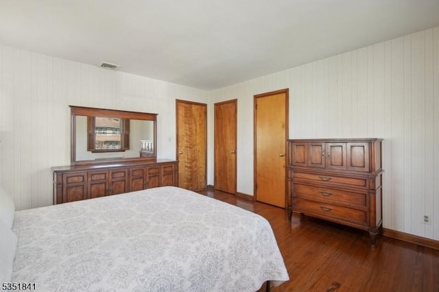 bedroom with visible vents, dark wood-type flooring, and two closets