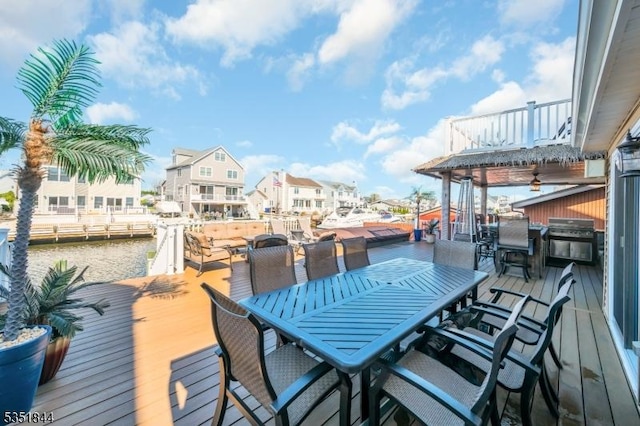 deck with outdoor dining area, a dock, and grilling area