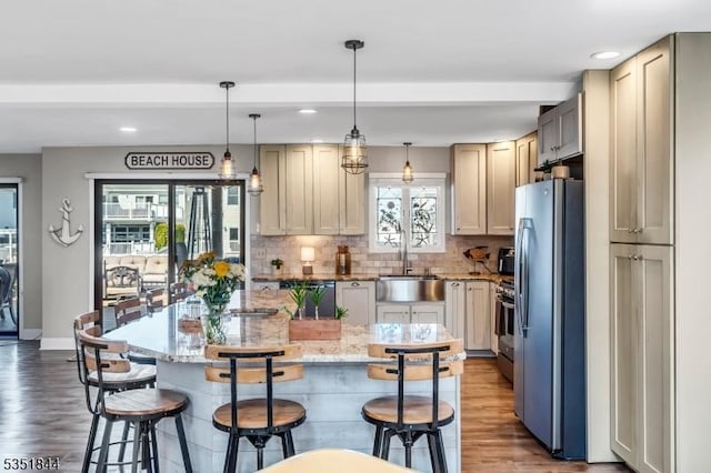 kitchen featuring a sink, dishwasher, freestanding refrigerator, decorative backsplash, and wood finished floors