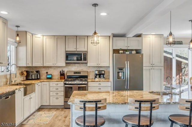 kitchen with a breakfast bar area, stainless steel appliances, a sink, and tasteful backsplash