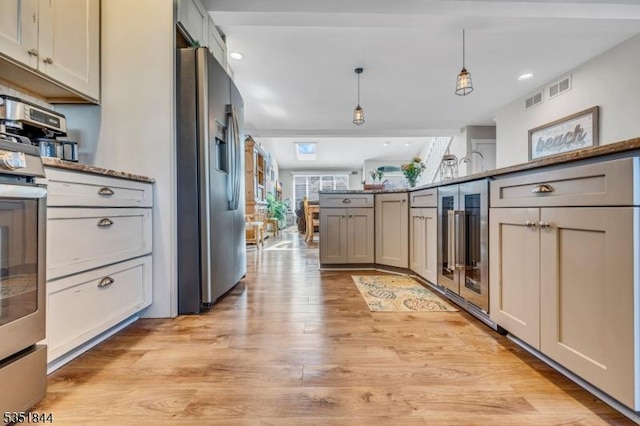 kitchen featuring visible vents, beverage cooler, stainless steel fridge, light wood-type flooring, and hanging light fixtures