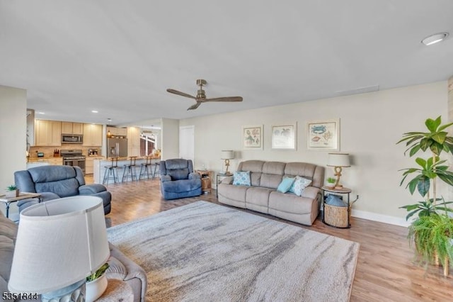 living area featuring baseboards, a ceiling fan, recessed lighting, and light wood-style flooring