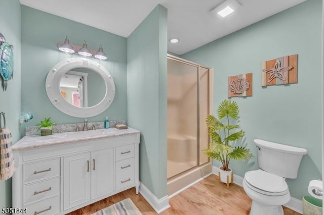 bathroom with a stall shower, wood finished floors, vanity, baseboards, and toilet