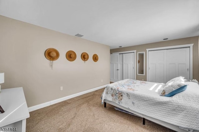 bedroom featuring carpet floors, baseboards, two closets, and visible vents