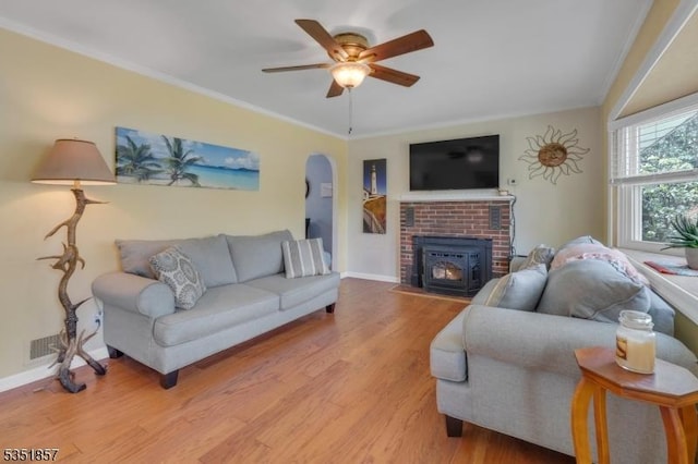 living area with crown molding, arched walkways, a ceiling fan, and wood finished floors