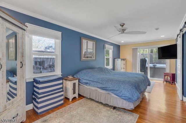 bedroom featuring baseboards, ornamental molding, wood finished floors, and a barn door