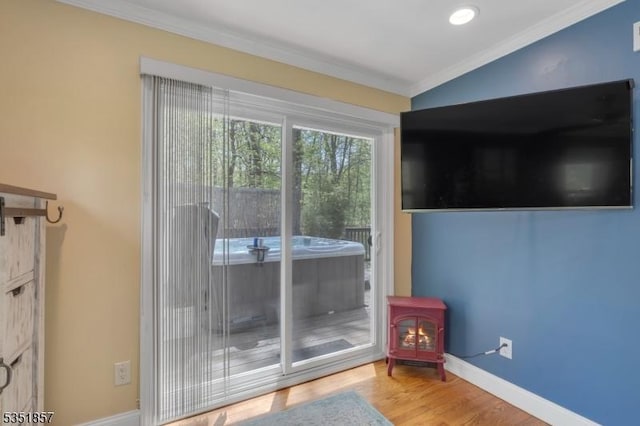 doorway featuring baseboards, ornamental molding, wood finished floors, and a wood stove