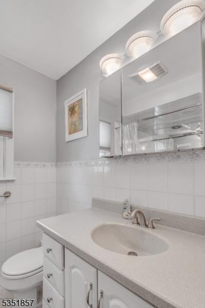 bathroom with tile walls, vanity, and toilet