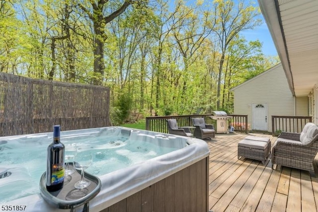 wooden deck with a hot tub and area for grilling