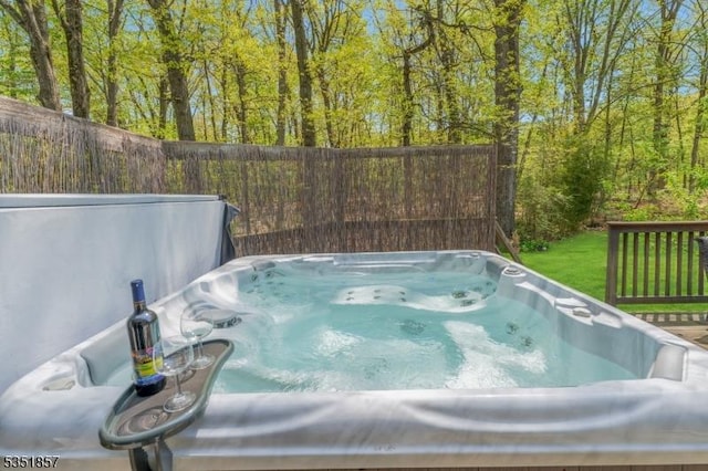 view of pool featuring a hot tub, a lawn, and a view of trees