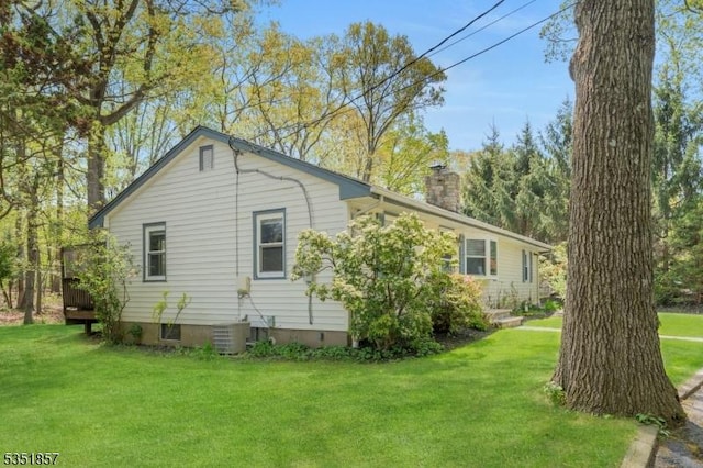 view of side of home with a yard, central AC, and a chimney
