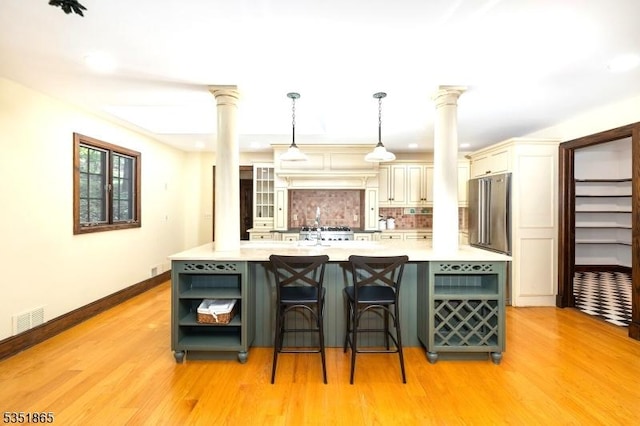 70 Friar Ln, Watchung Boro, NJ 07069 - kitchen featuring decorative columns, cream cabinets, tasteful backsplash, light countertops, and light wood finished floors