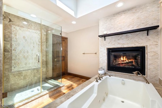70 Friar Ln, Watchung Boro, NJ 07069 - bathroom with wood finished floors, a jetted tub, a stall shower, a glass covered fireplace, and baseboards