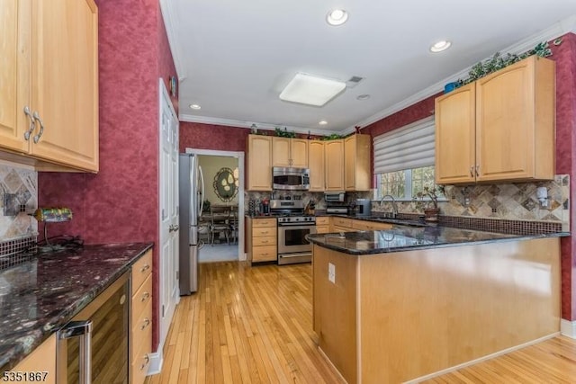 kitchen with decorative backsplash, ornamental molding, light wood-style floors, a sink, and stainless steel appliances