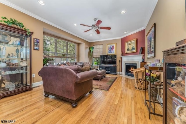 living room with ceiling fan, a fireplace with flush hearth, hardwood / wood-style flooring, ornamental molding, and recessed lighting